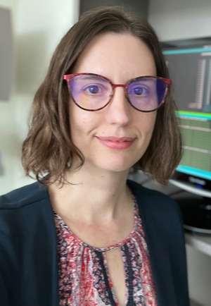professor wearing a black sweater and pink shirt shirt in a lab backdrop